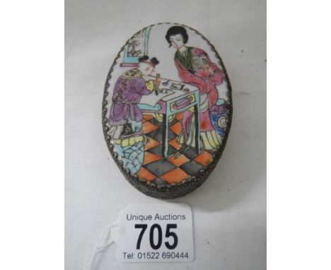 An oval pill box with enamel top.