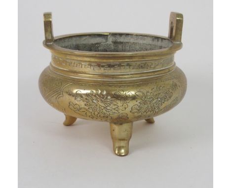 A CHINESE BRASS INCENSE BURNER with lug handles above a key pattern band and decorated with precious objects, trellis and fol