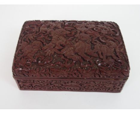 A CHINESE CINNABAR BOX AND COVER carved with kylin with precious objects and ribbons, above scrolling foliage, 7cm high, 18cm