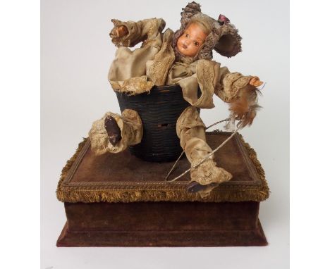 AN EARLY 20TH CENTURY AUTOMATON in the form of a baby doll in basket clothed in Victorian style lace bloomers and frilled bon