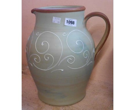 A large Denby stoneware jug with tube-lined scroll decoration on a light green ground