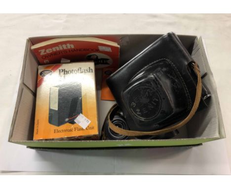A box containing a vintage Zenit-E camera with Pentacon lens, Boots photoflash, instruction manual, etc.