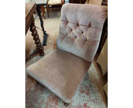 A late Victorian nursing chair with button back velour upholstery, set on turned front legs with brown porcelain casters