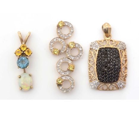 Three gem set pendants, one with opal, topaz and orange sapphires, one yellow and white stones, the third black and white sto