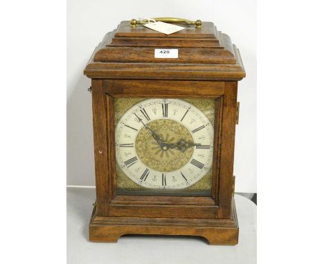 A German oak-cased mantel clock, the silvered chapter ring with roman numerals in black, enclosed by a glazed door, raised on