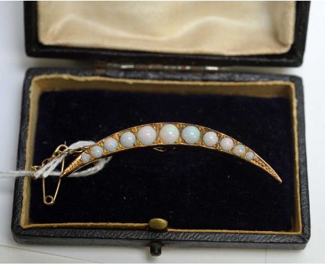 An early 20th Century opal crescent brooch, set with eleven graduated opal cabochons, in yellow metal mount with balustrade g