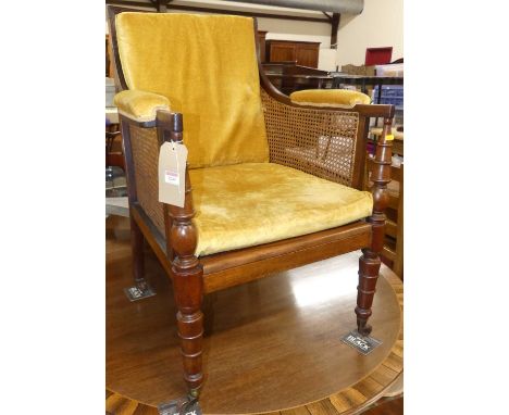 A 19th century mahogany and cane inset Bergere chair by Jas Shoolbred, having mustard fabric squab cushions and padded arms, 