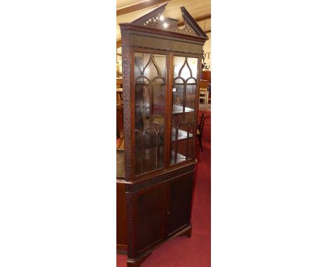 A circa 1900 mahogany freestanding corner cupboard in the Chippendale taste, having pierced architectural pediment, over twin