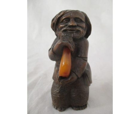 A small wooden carved figure ( possibly Russian) of a bearded man holding a piece of amber, marked I K to base), 12cm height