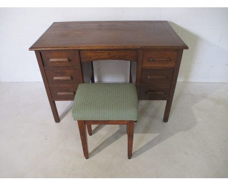 A vintage oak writing desk, along with an upholstered stool
