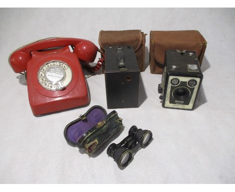 A vintage red telephone, along with a pair of cased opera glasses and two Brownie camera's