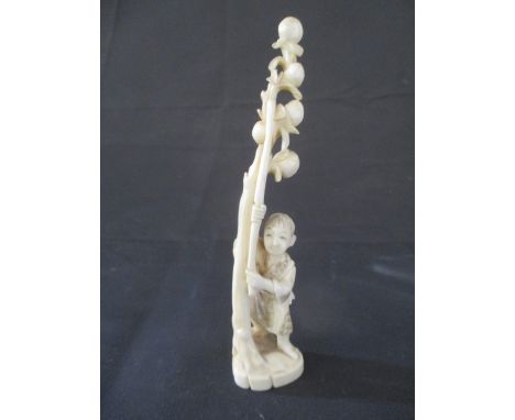 A 19th Century Japanese ivory Okimono of a young boy holding a stick by a tree containing fruit, 14.5cm height