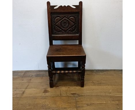 A 17th century single chair, with a carved panel back and seat, on turned legs 