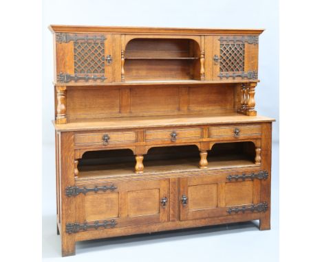 AN ARTS AND CRAFTS OAK SIDEBOARD, IN THE MANNER OF LIBERTY &amp; CO, the upper section with a pair of fret work carved and gl