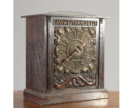 AN ARTS AND CRAFTS OAK MOTTO MANTEL CLOCK, with leaf-form copper dial below the motto 'EAST WEST HAMES BEST', the front furth