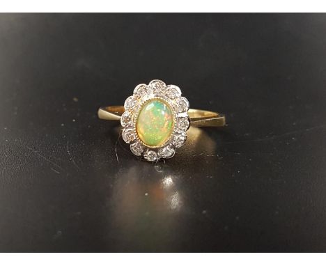 OPAL AND DIAMOND CLUSTER RINGthe central oval cabochon opal in twelve diamond surround, on eighteen carat gold shank, ring si