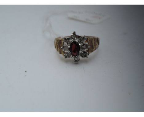 A lady's dress ring having a garnet and diamond cluster in an illusionary setting to decorative shoulders on a 9ct gold loop,