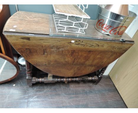 A 19th century oak dining table in the 17th century style having oval top and frieze drawer on bobbin gate legs