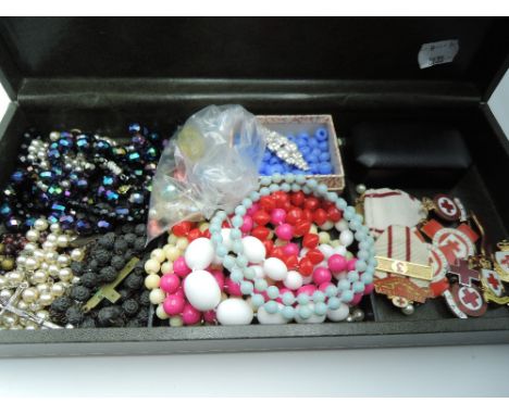 A modern jewellery box containing a small selection of jewellery including Red Cross Society brooches and medal, Rosary beads