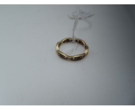 A yellow metal eternity ring of shaped form set with garnets and CZ,  size Q
