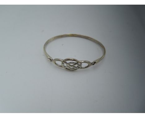 A white metal tension bangle stamped 925 having a Celtic knot clasp