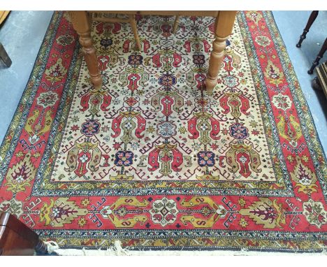 Turkish wool carpet, the cream filed with repeat stylised gul design in rust, blue and yellow tones, enclosed in similar bord