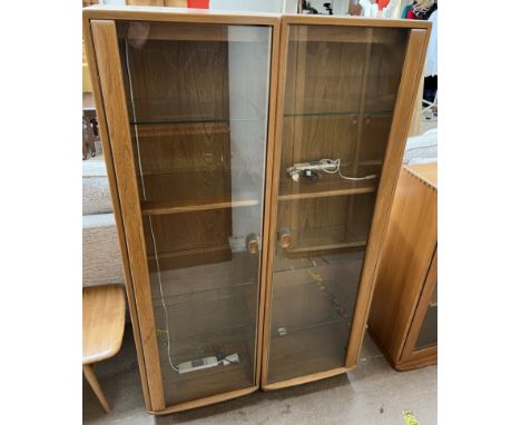 A pair of Ercol light elm display cabinets with a glazed door and shelves, each 46.5cm wide x 153cm high 