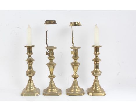 Pair of Victorian brass candlestick, with tapering stems, domed lower sections and square bases, with attached shade holders,