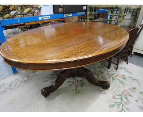 A late Victorian mahogany loo table with a turned, tapered, carved column, on a tripod base and castors