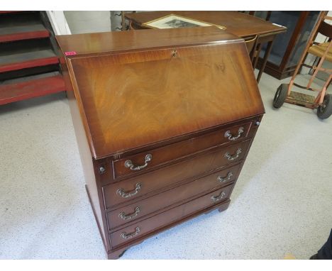 A reproduction mahogany four drawer bureau on bracket feet