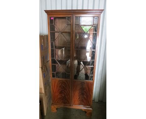 A reproduction mahogany glazed bookcase having a dental moulded cornice and a pair of glazed panelled doors on bracket feet