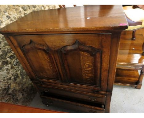 A Titchmarsh and Goodwin style oak television cabinet with a rise and slide door, over two drawers, on bracket feet and casto