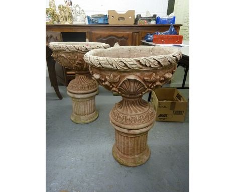 A pair of composition stone garden urns on pedestal bases