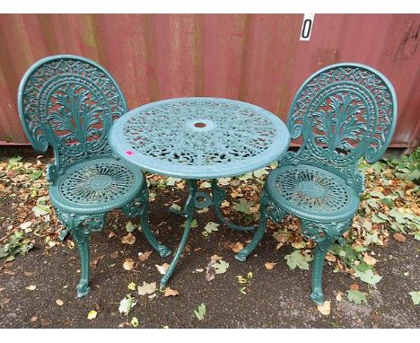 A modern green painted, cast metal garden table, along with a pair of garden cast metal chairs