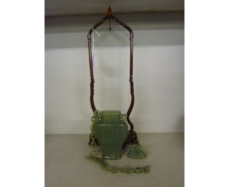 A 20th Chinese carved green jade suspended vase and cover, the shouldered pear shaped body with pierced handles, lion dog fin