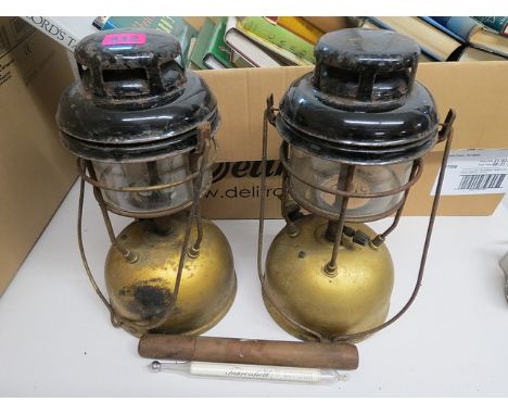 A pair of black and gold painted metal oil lamps and a cased thermometer