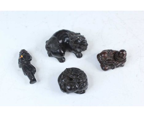 Four Japanese dark wood netsuke, Meiji era, 19th to 20th century. The first carved as a ferocious lion seated on its haunches