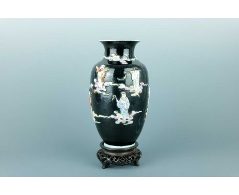 A Chinese black ground moulded ‘Eight Immortals’ vase, Qing Dynasty, 19th century. The vase of slightly tapered form standing