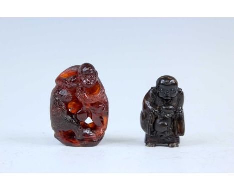 A Japanese amber netsuke of two monkeys, Meiji era, 19th century, together with a second netsuke of a monk wearing a robe, po