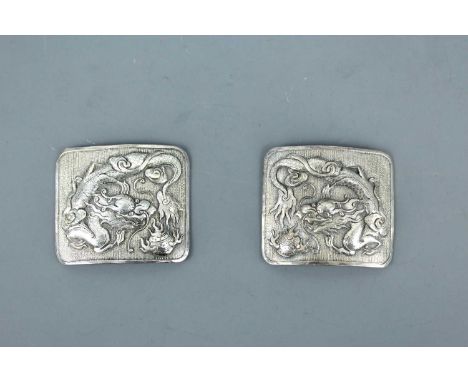 A pair of Chinese silver ‘dragon’ buckles, late 19th or early 20th century. Each of slightly convex rectangular form, repouss