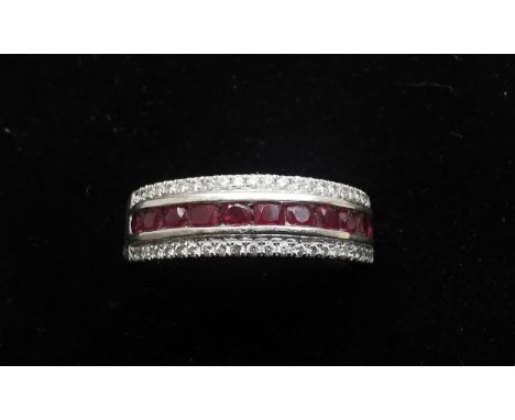 An 18ct white gold ruby and diamond half eternity ring, set with a channel of eleven oval mixed cut rubies with an approximat