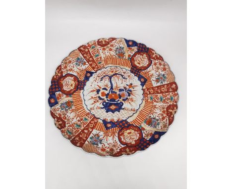 A large 19th century Japanese scalloped edge Imari pattern charger with gilt detailing decorated to the centre with a blossom