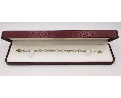 A vintage boxed 14 carat white and yellow gold diamond articulated line bracelet. The bracelet is set with fourteen round bri