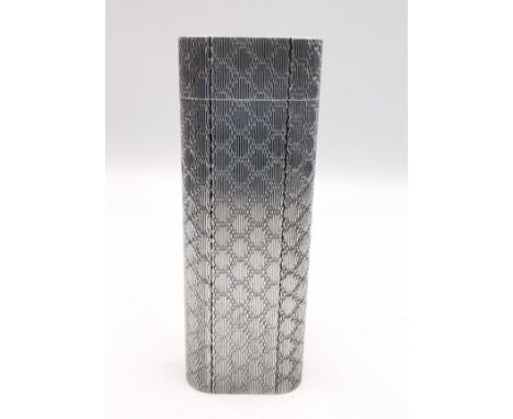 A white metal lighter by Cartier Paris. The lighter of flattened cylindrical form having engine turned net decoration. Signed