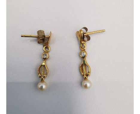A pair of yellow metal (tests higher than 9ct) cultured pearl and diamond drop earrings. Each earring is set with a 0.03 cara