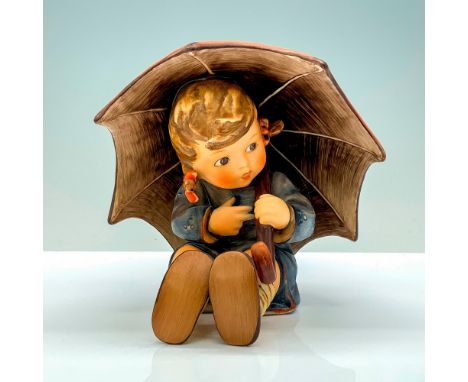 A figure of a young girl with pig tails and a blue rain jacket holding a red umbrella over her head. Goebel Hummel backstamp.
