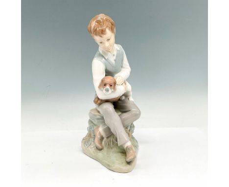 Glossy figurine of a boy seated on a rock holding his dog. Item #603. Issued: 1982Dimensions: 6.5"L x 4.5"W x 10"HManufacture