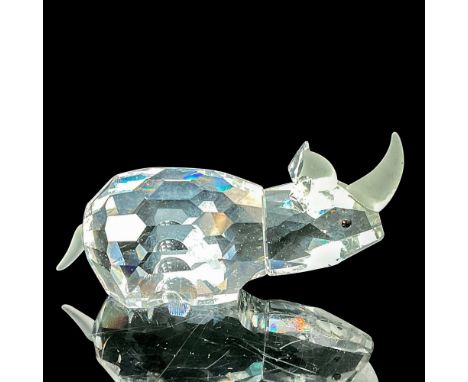 The small rhino figurine is crafted from clear crystal, featuring black eyes, and adorned with frosted horns and tail. This i