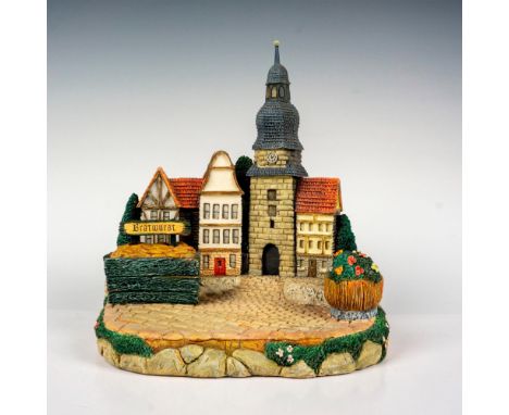 Hand painted stand featuring cobblestone streets, with little shops, a clock tower, flowers and Bratwurst. Part of the Hummel