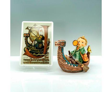 A figure of a young child sitting on a canoe holding a horn with a small yellow bird accompanying him along with a postcard m